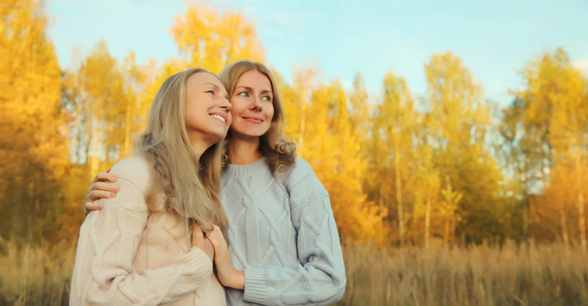 Portrait of happy two women, smiling mature mother and adult daughter hugging in autumn park